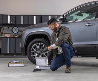 A Man Working on Vehicle Items While Kneeling Next to Vehicle