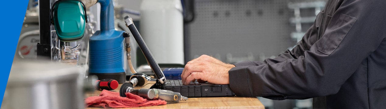 Technician Typing on a Laptop While Standing at a Work Desk