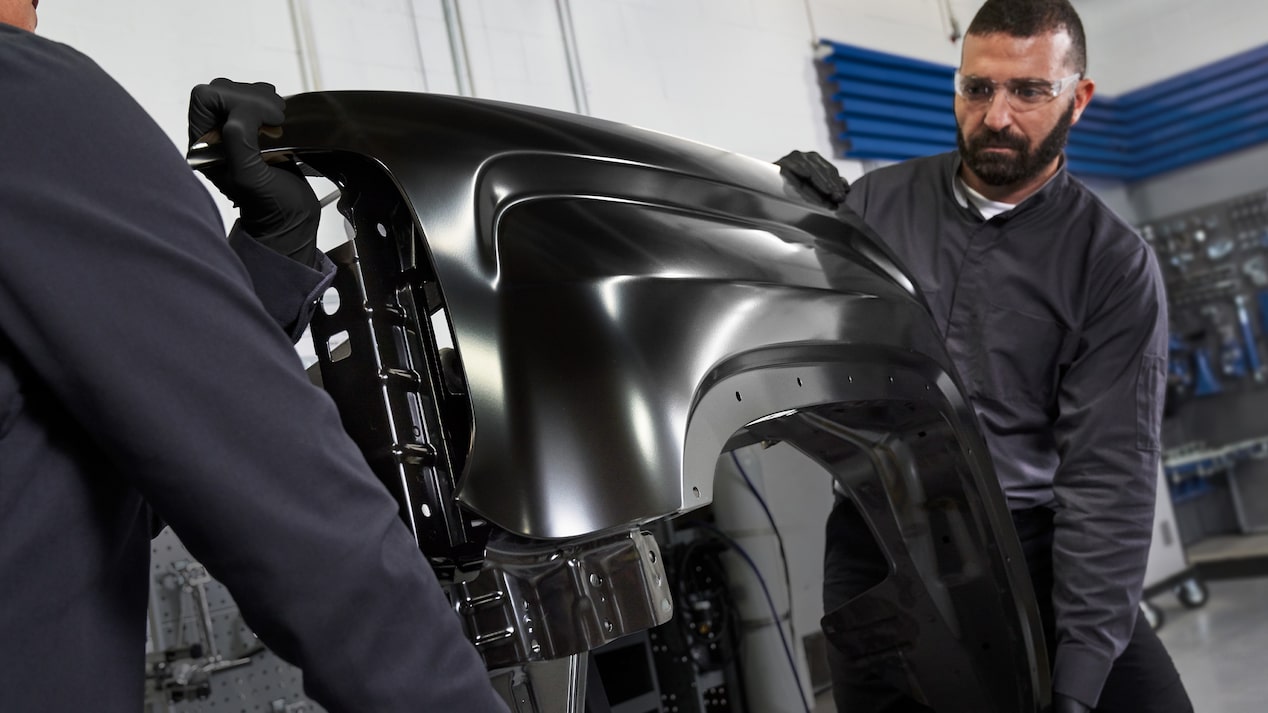 GM Technician Holding a Spark Plug and Working on a Vehicle