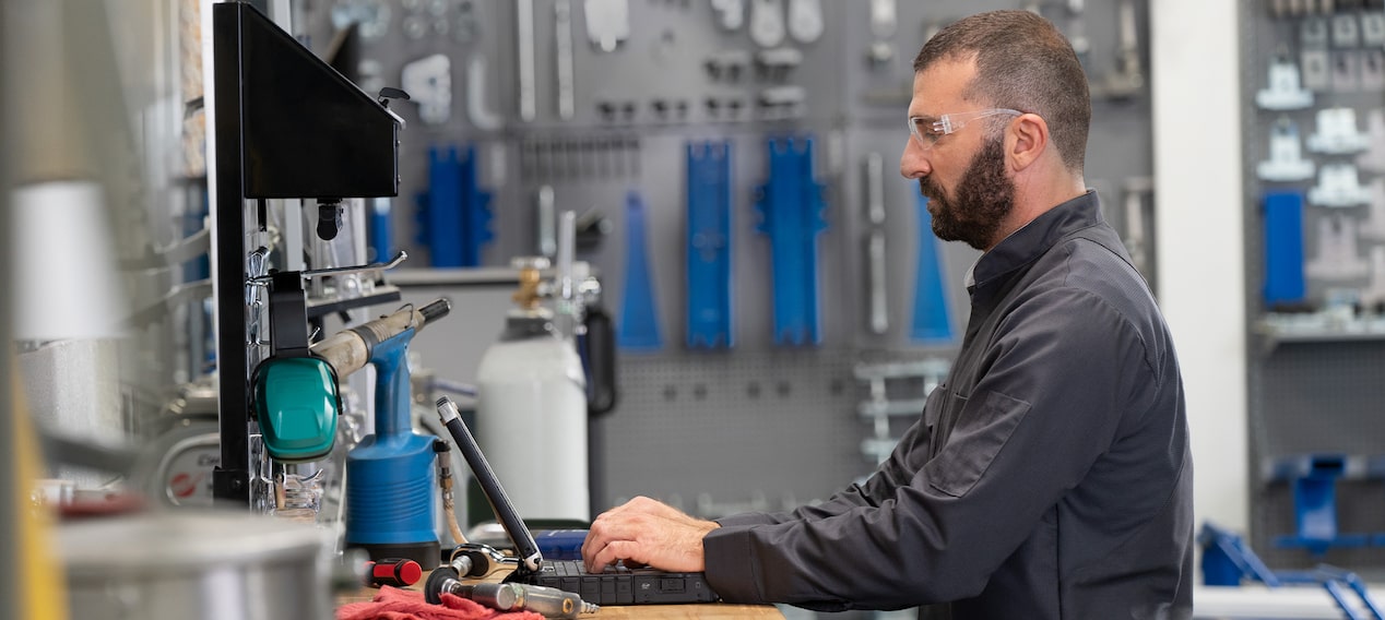 Technician Standing at a Work Station Typing on a Laptop