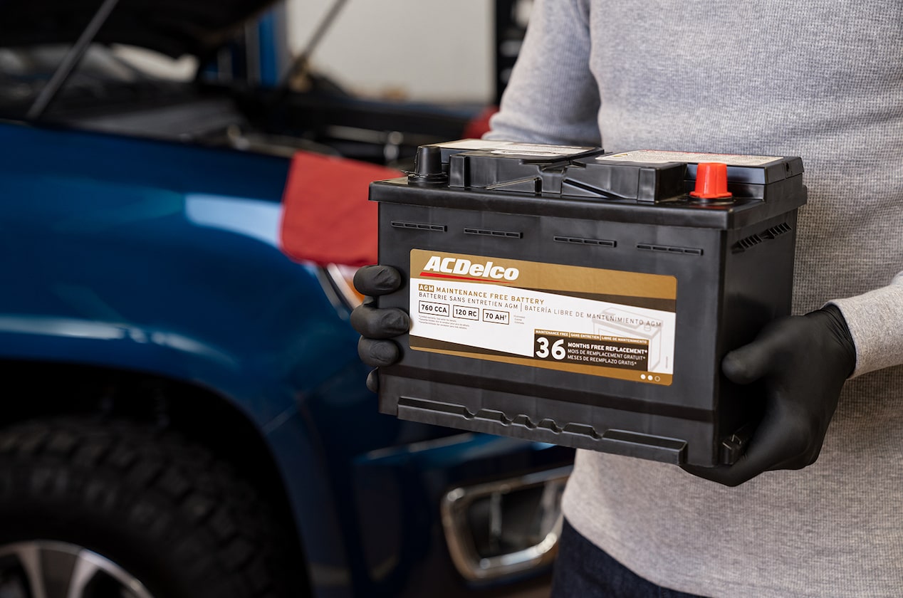 A Person Standing Next to Their Vehicle Holding an ACDelco Gold Battery