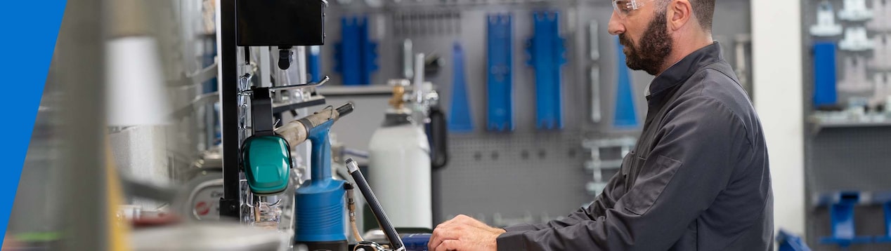 GM Technician Standing at a Work Desk and Typing on a Laptop