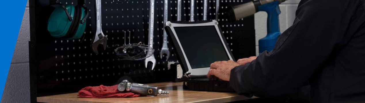 Technician Standing at a Work Bench Typing on a Laptop