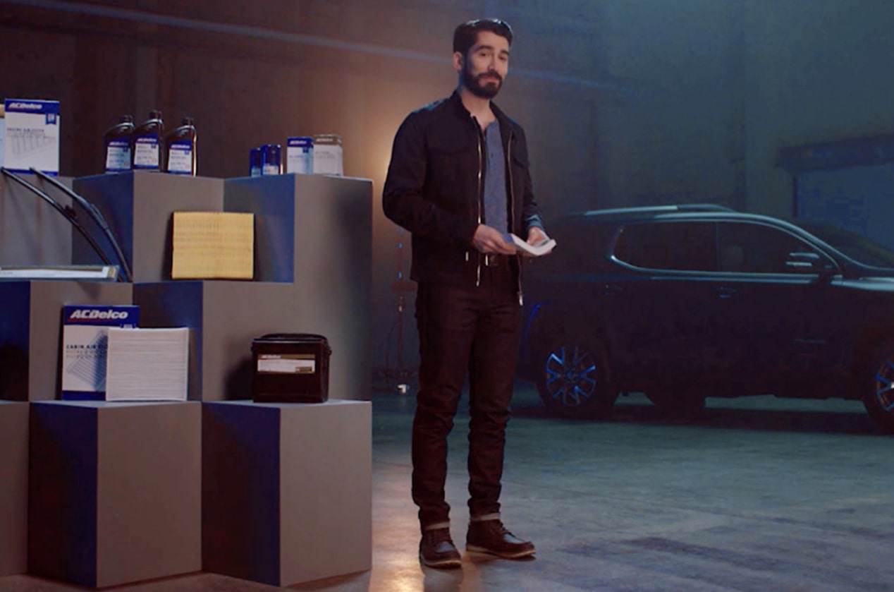 A Man Standing Next to an ACDelco Parts Display With a Vehicle in the Background